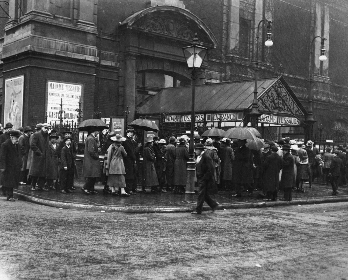 1930: gente in fila sotto la pioggia fuori dalla fabbrica delle cere di Madame Tussaud a Londra.