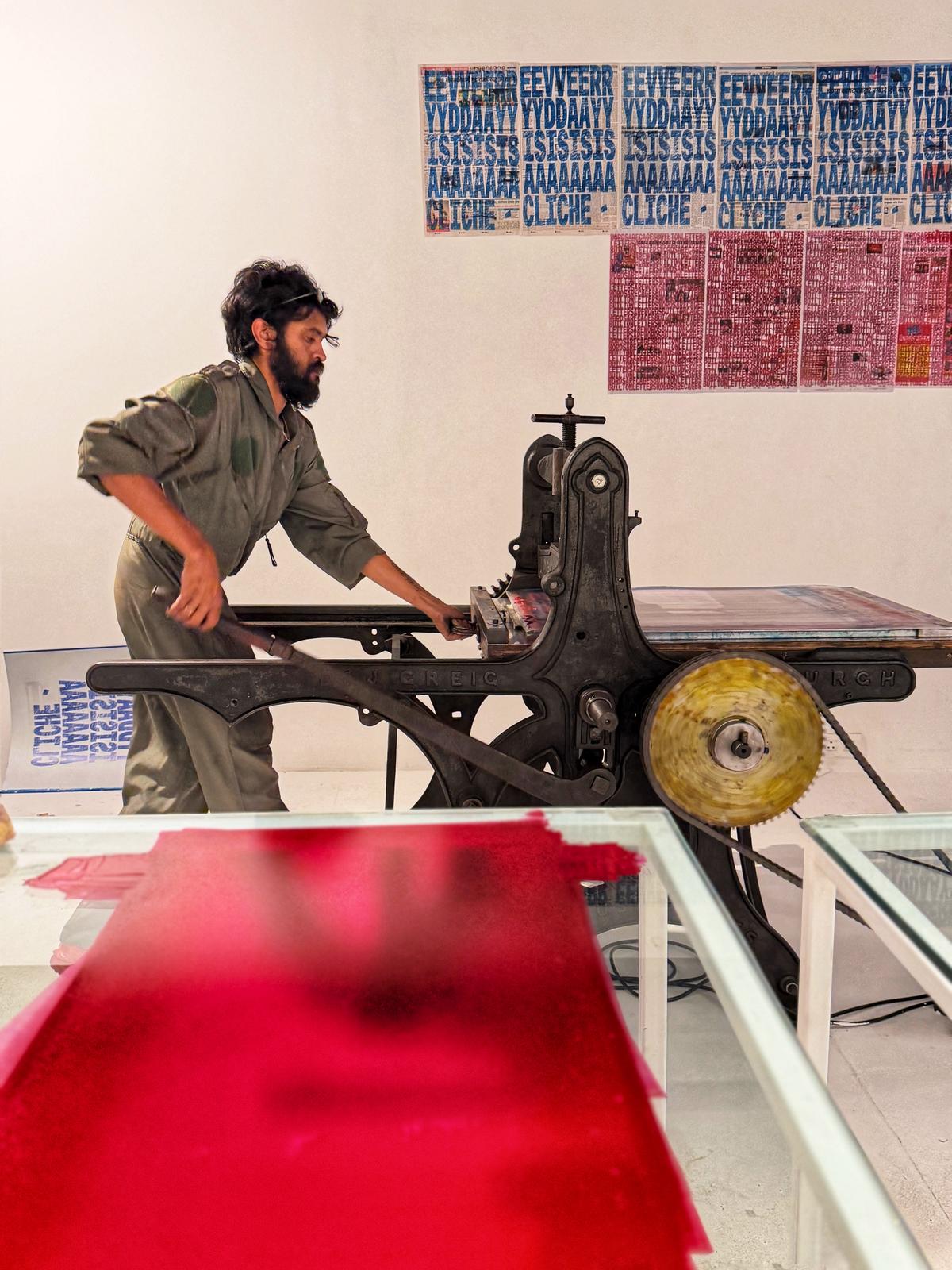 Artist Jayasimha Chandrashekar printing the phrase Every day is a cliché on the day’s newspaper on a litho press. 