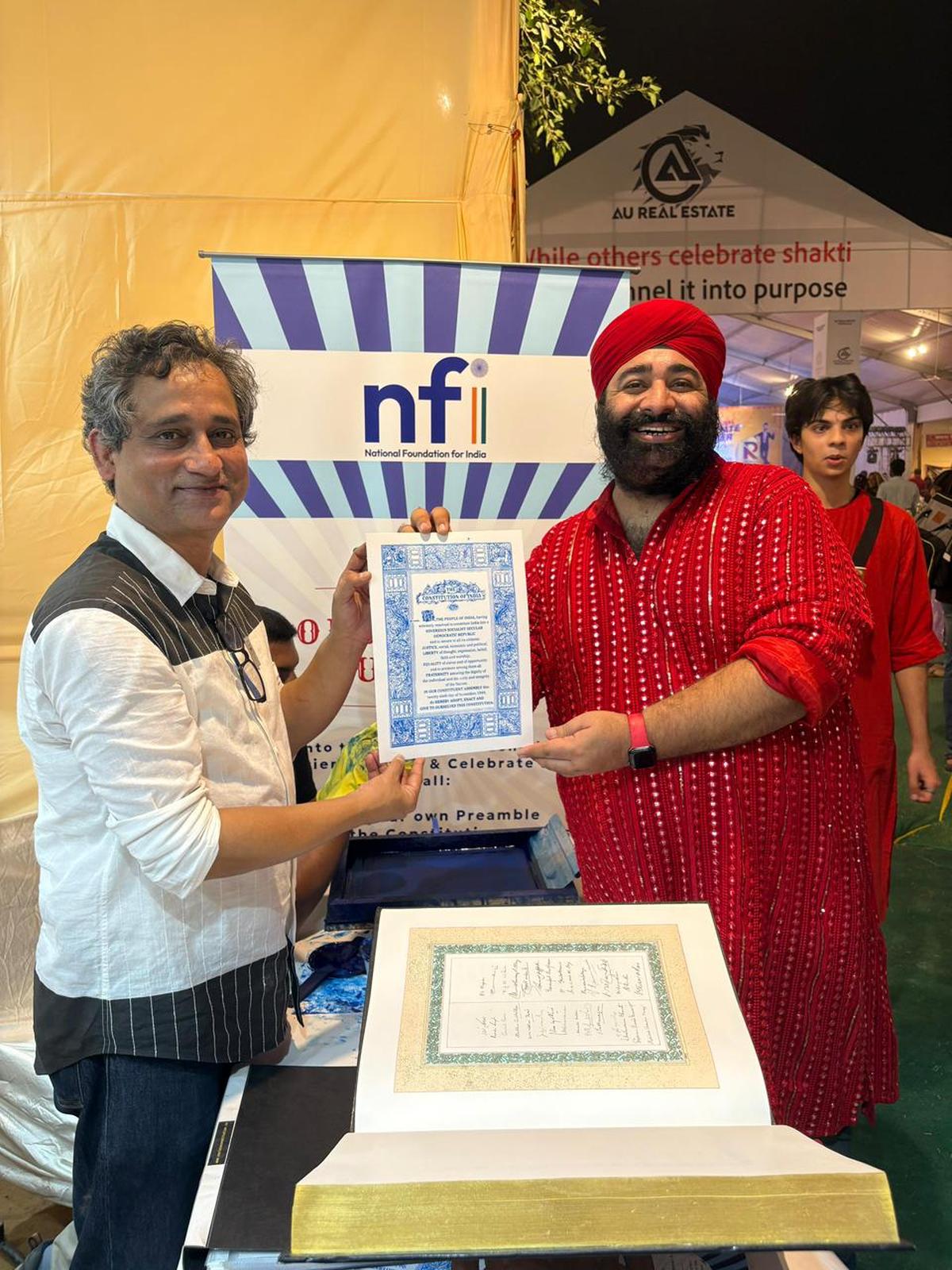 Biraj Patnaik, executive director of the National Foundation for India presents a copy of the Preamble to a visitor at the Uday Shankar Park Durgotsab, Greater Kailash II, Delhi