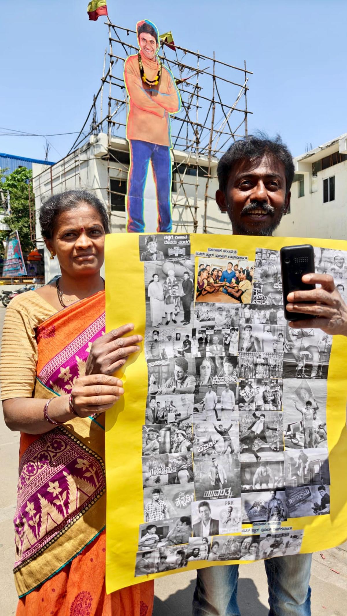 Fans with a collage of famous characters of actor Puneeth Rajkumar outside a single screen showing the film ‘Appu’.