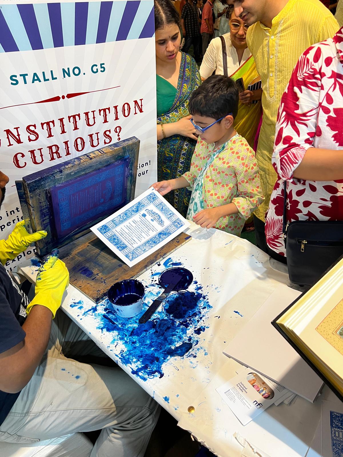 Visitors screen-print a copy of the preamble at the National Foundation for India’s Constitution Curious pop-up stall in collaboration with Reclaim Constitution, at the Uday Shankar Park Durgotsab, Greater Kailash II, Delhi