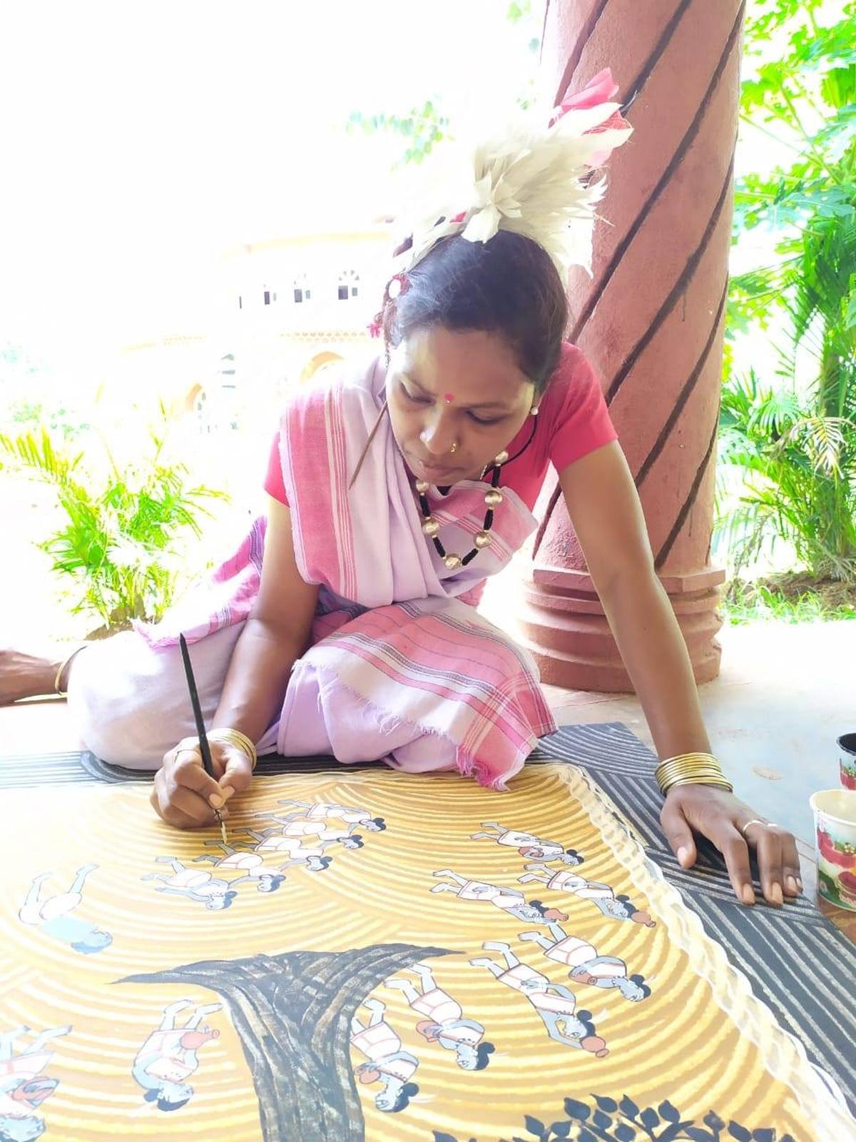 एक उराँव कलाकार अपनी पेंटिंग को अंतिम रूप दे रही है।