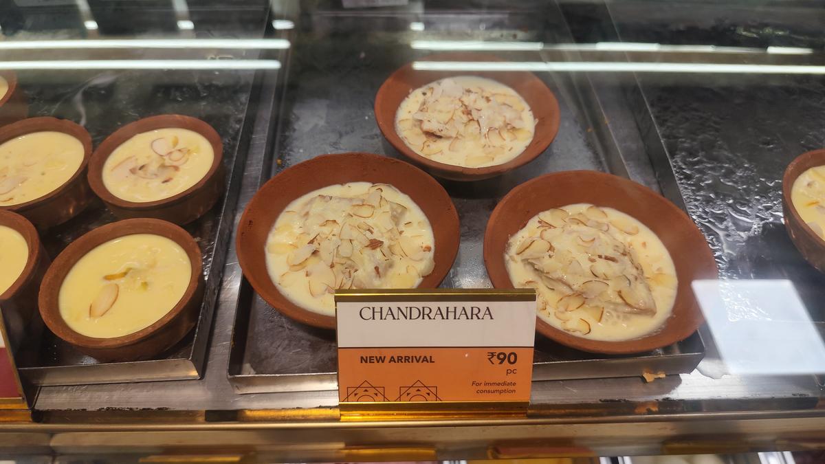 The sweet has a crispy folded pastry that is topped with a rabdi and chopped nuts