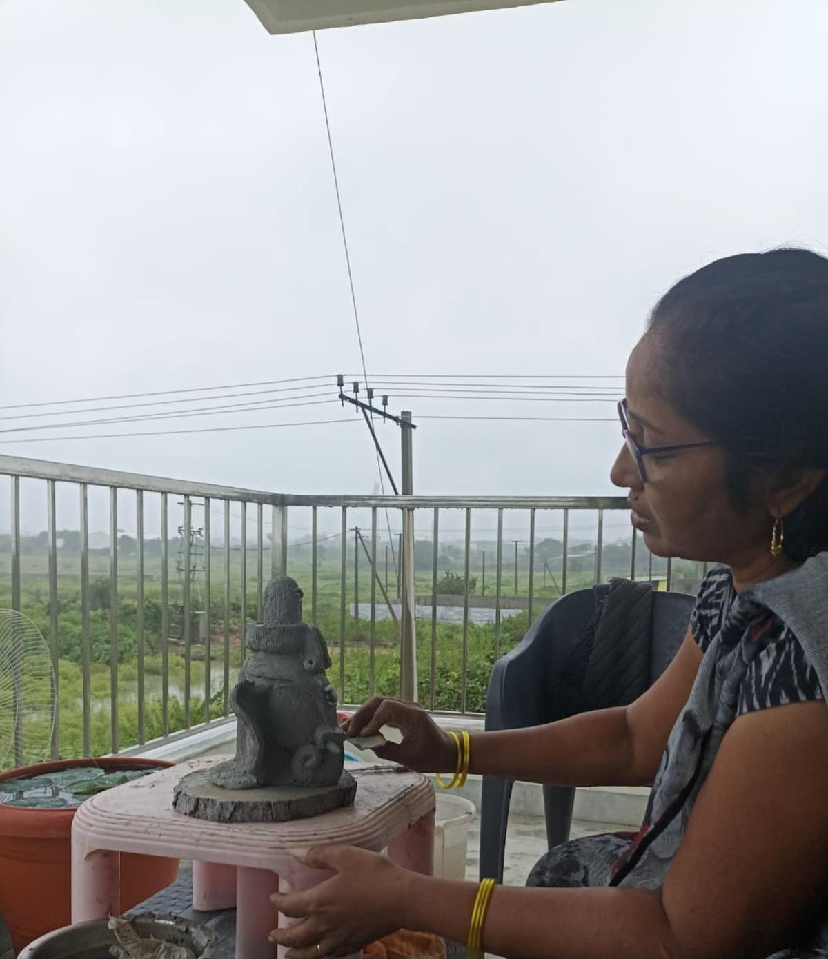 Artist Saraswathi carving a clay Ganesha at home 