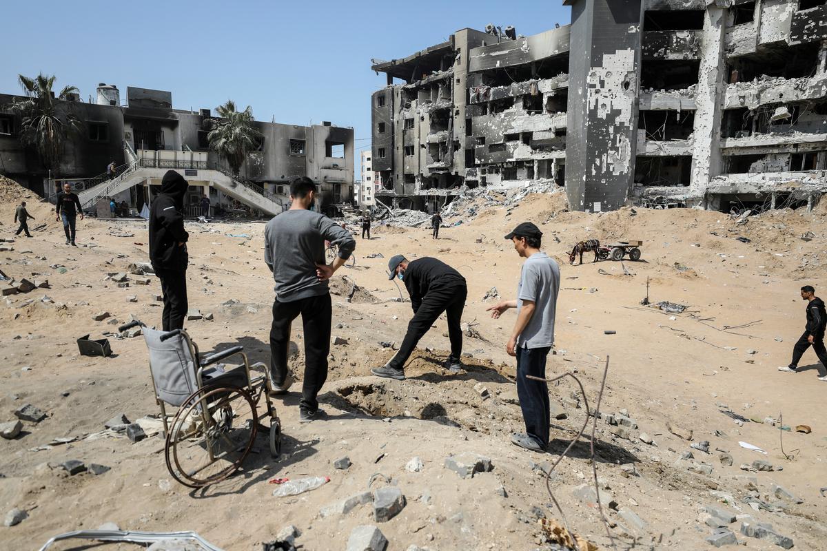 Palestinians use shovels to search for dead bodies of their relatives near Al Shifa Hospital after Israeli forces withdrew from the hospital and the area around it following a two-week operation, amid the ongoing conflict between Israel and Hamas, in Gaza City on April 2, 2024. 