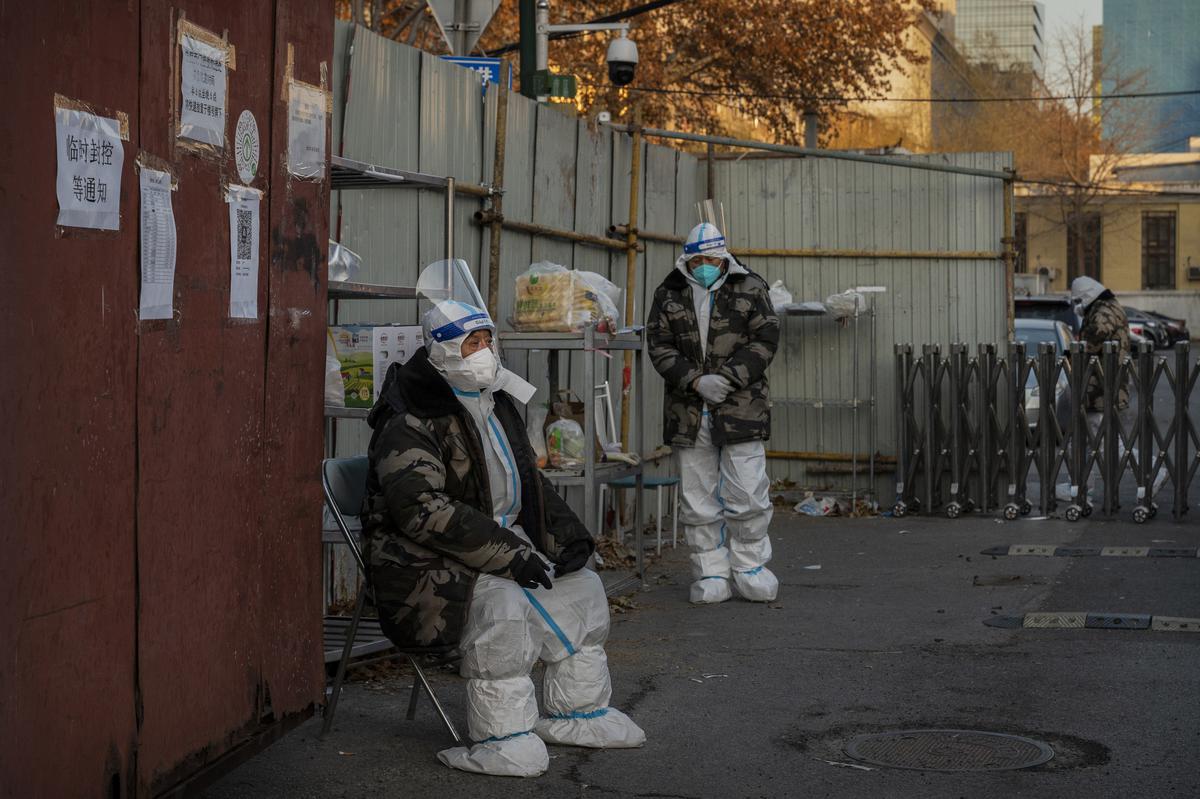 Security guards wear PPE as they guard outside a community in an area with residents under health monitoring or lockdown for COVID-19 on December 4, 2022 in Beijing, China.