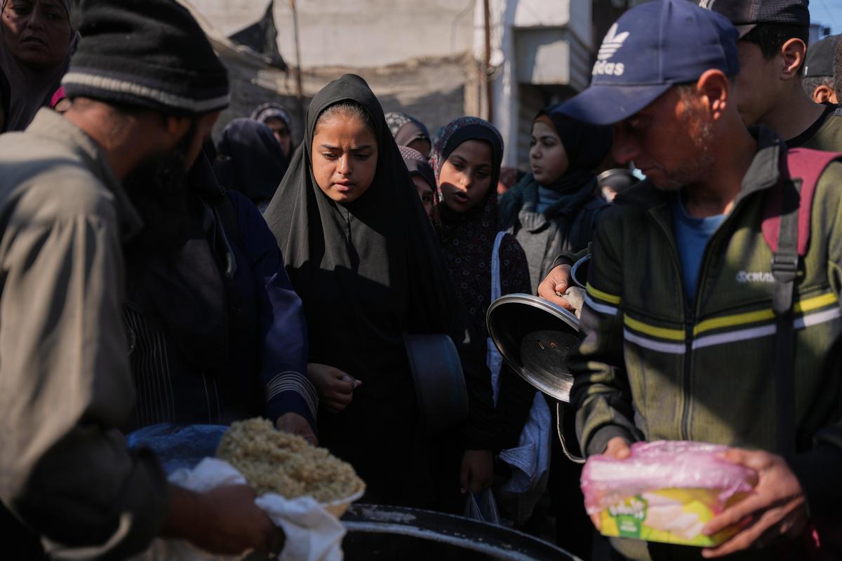 Palestinians women line up to receive donated food at a community kitchen in Deir al-Balah, central Gaza Strip, on Thursday, Dec. 25, 2025. 