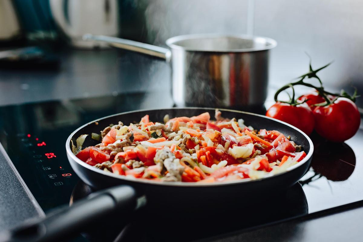 Frying minced pork with vegetables on olive oil. Frying pan on induction cooker. Preparing spaghetti bolognese sauce for dinner Inducation