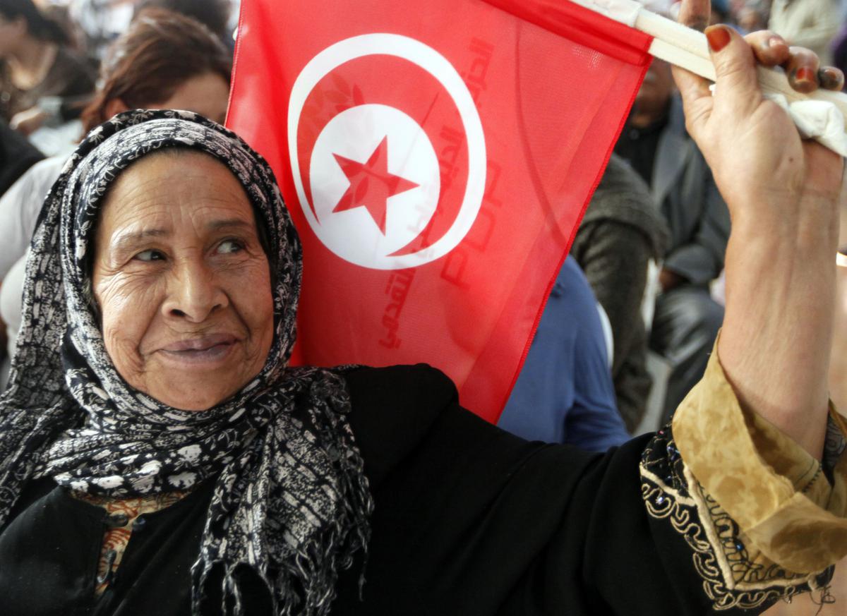 أحد مؤيدي حزب التقدم الديمقراطي يلوح بالعلم التونسي خلال تجمع حاشد في منطقة أريانة جنوب تونس في عام 2011.