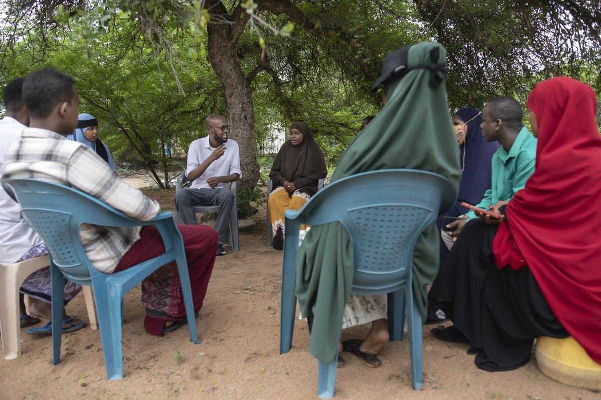 This handout picture taken on November 10, 2023 and made available on November 28, 2023 by the UNHCR shows Abdullahi Mire (centre-left) meeting with youth in Kenya’s Dadaab refugee camp.