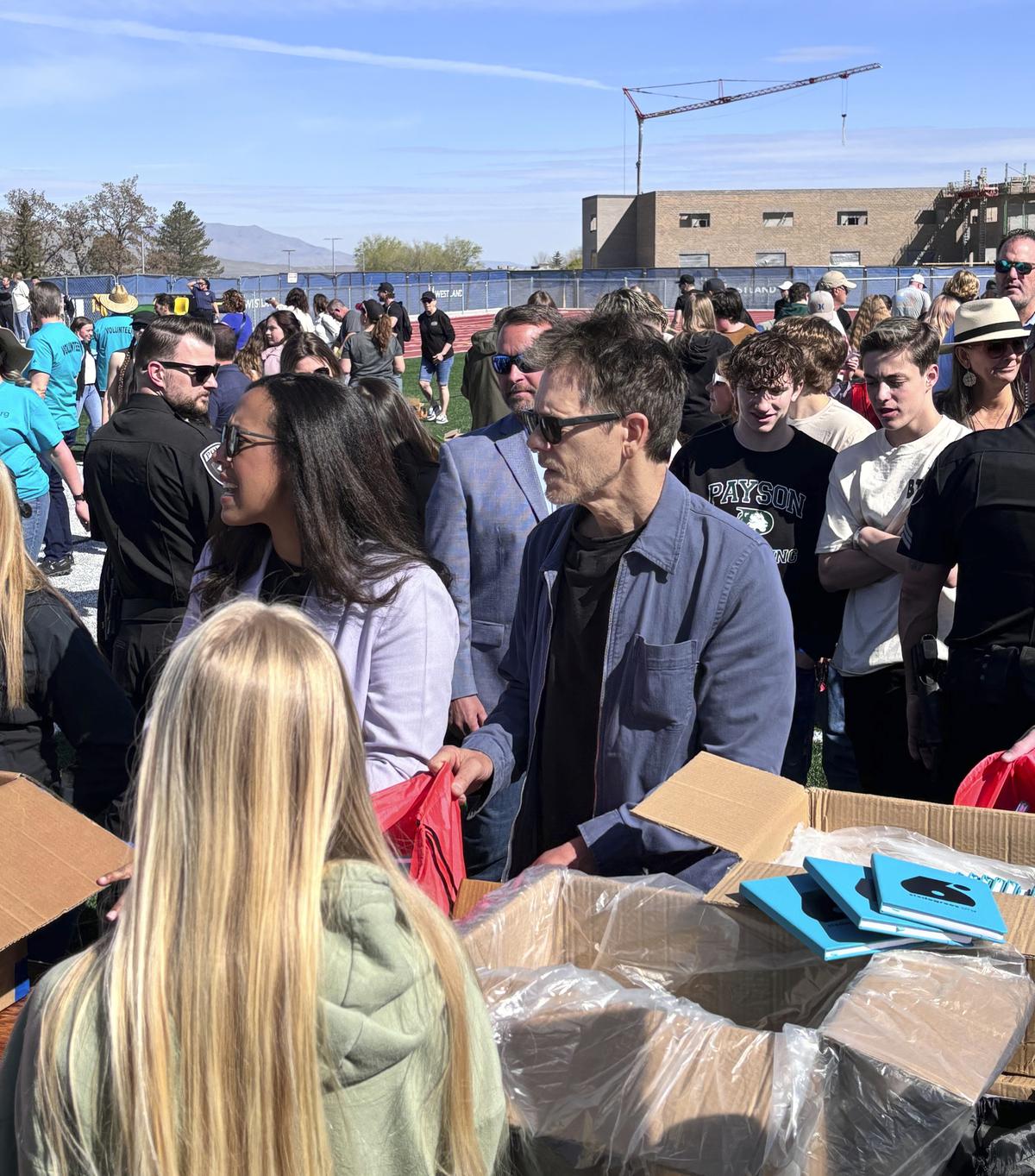 Actor Kevin Bacon, center, helps fill care packages for his charity, Saturday, April 20, 2024, in Payson, Utah, while visiting the Utah high school where cult classic “Footloose,” was filmed.