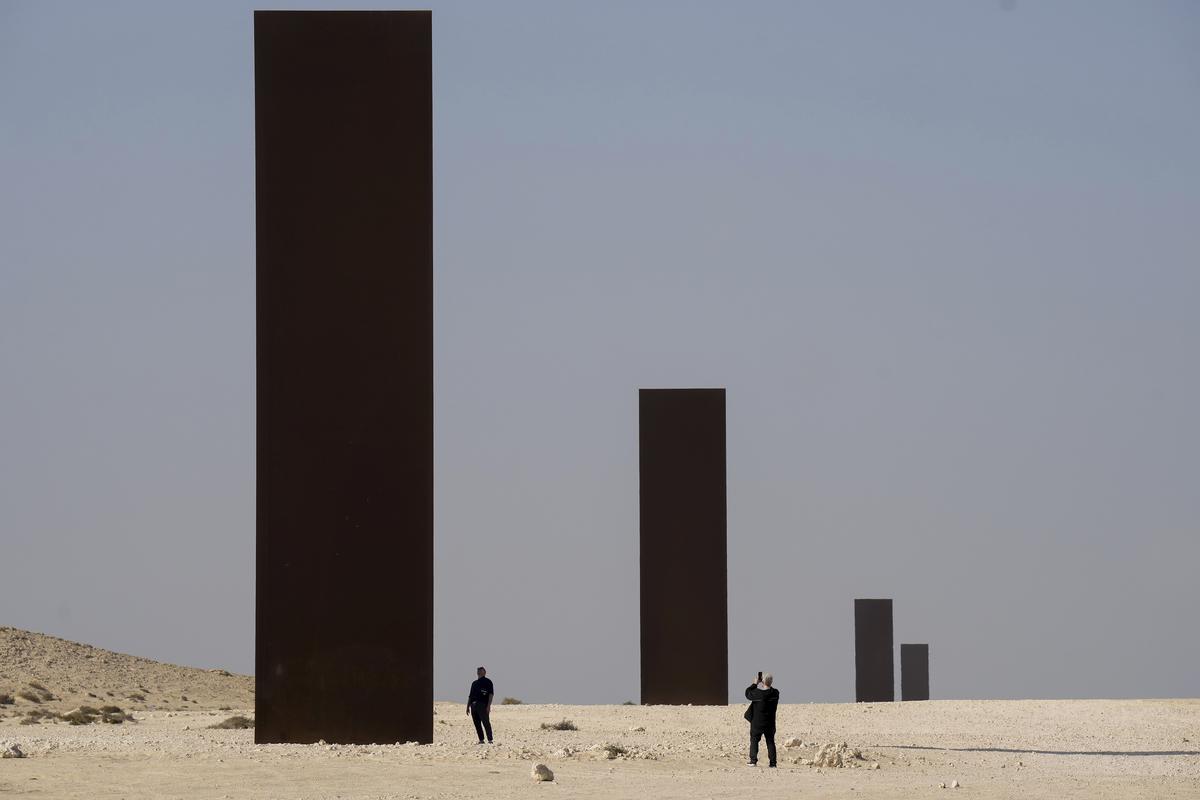People view American artist Richard Serra’s “East-West/West-East” art as it stands in a desolate section of the Brouq Nature Reserve in the northwestern part of the country’s desert close to Zekreet, Qatar, Dec. 3, 2022. 