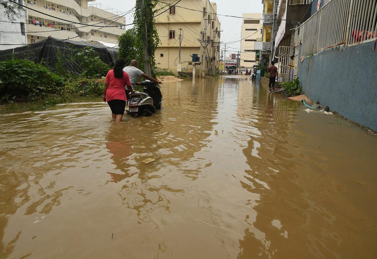 Students from a hostel tread carefully in the flood water that inundated roads of Maisammaguda area on the outskirts of Hyderabad on Tuesday.