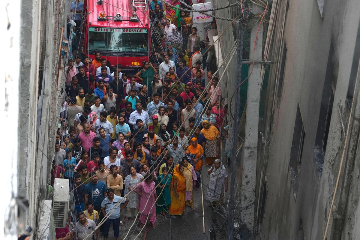Moradores e transeuntes assistem a um incêndio em um hotel enquanto os bombeiros trabalham para apagar as chamas em Nova Delhi