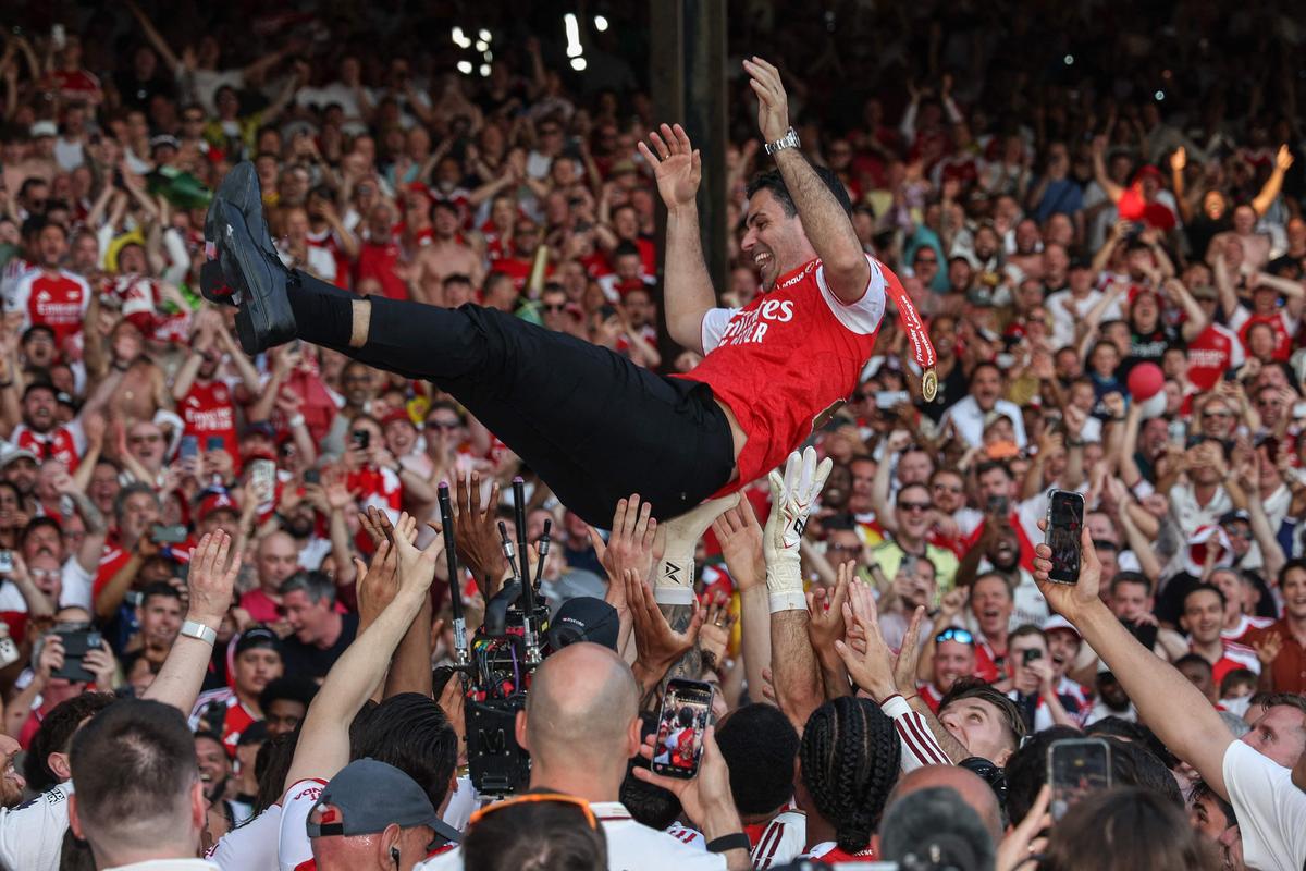 Arsenal players and staff throw Arteta into the air. Arsenal players and staff throw Arteta into the air.