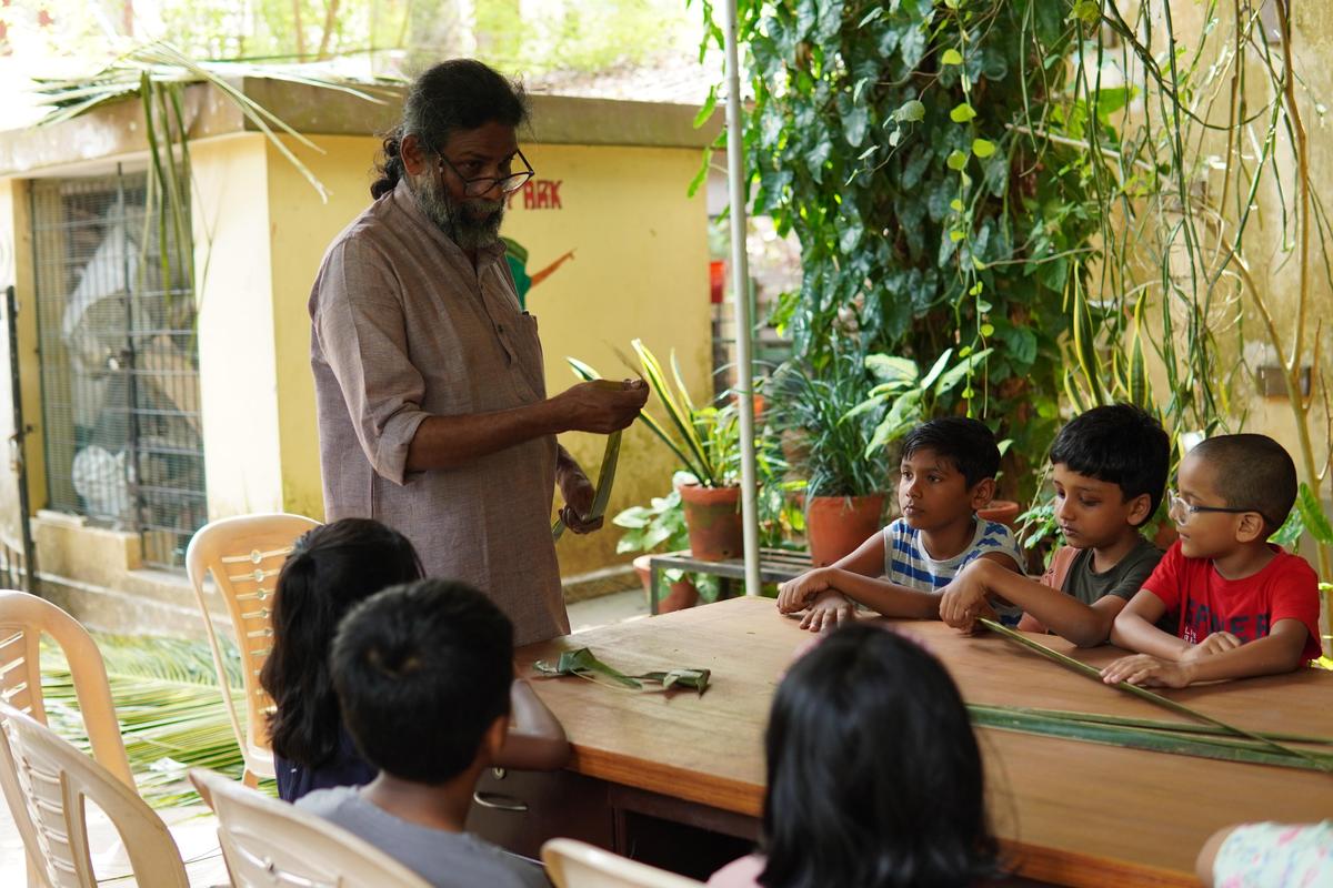 Artist and sculptor John Baby teaching children how to make toys from palm leaves at Thalir summer camp in Thiruvananthapuram
