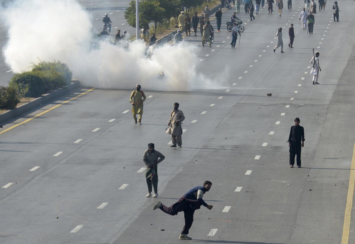 Supporters of imprisoned former premier Imran Khan’s Pakistan Tehreek-e-Insaf party, throw stones as police fire tear gas shell to disperse them during clashes, in Islamabad, on November 26, 2024.