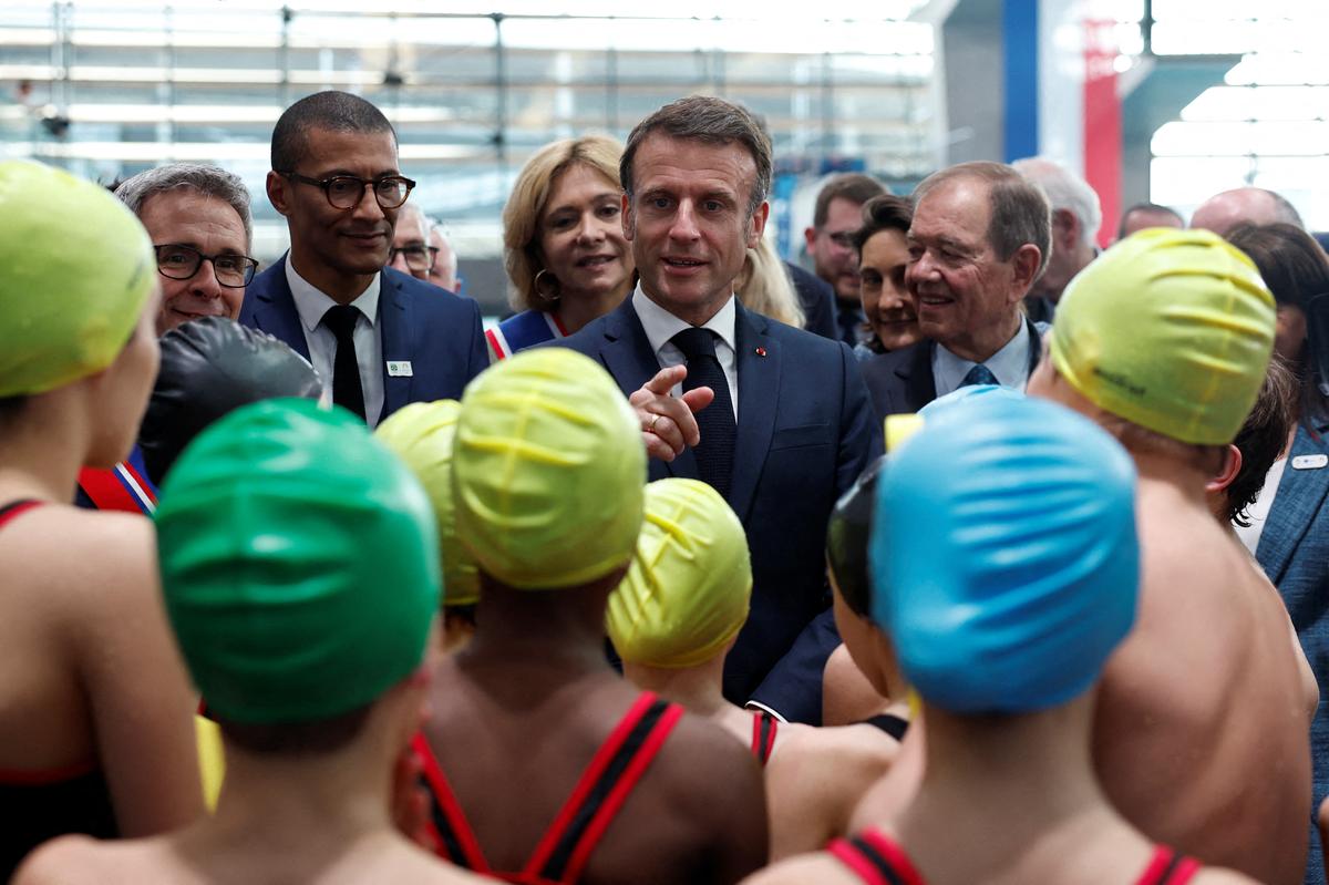French President Emmanuel Macron talks to young swimmers during the inauguration of the Olympic Aquatics Centre in Paris.