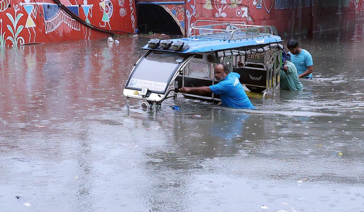 People push an e-rickshaw through a severely waterlogged road following heavy rainfall, in Mathura. People push an e-rickshaw through a severely waterlogged road following heavy rainfall, in Mathura.