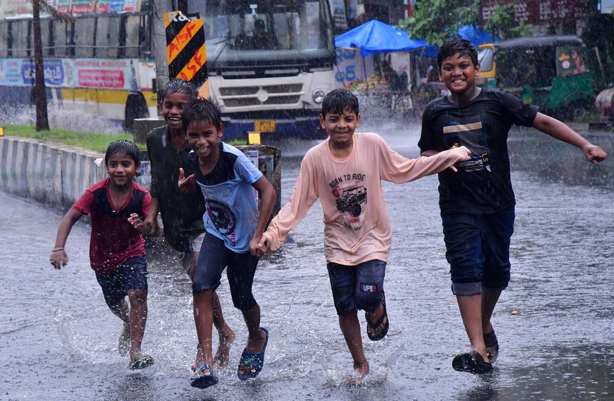 Children enjoying the rain on Eluru Road in Vijayawada on Sunday.    