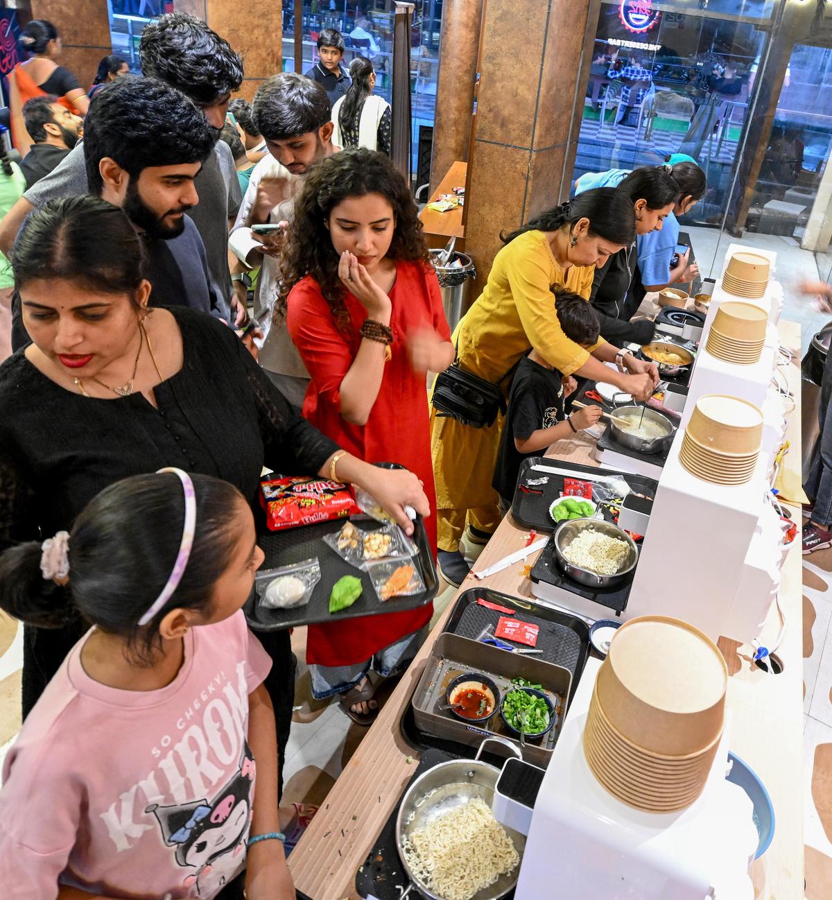 विशाखापत्तनम में बीच रोड पर नव-खुले रेस्तरां जेन्ज़ राम्युन, एक स्व-सेवा कोरियाई राम्युन बार, में लोग अपनी रामयुन बनाते हुए।