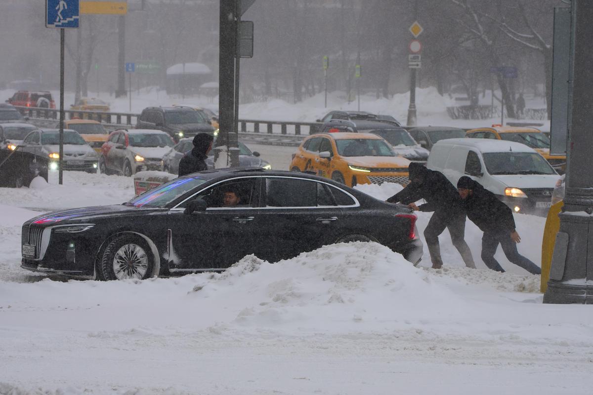 People try to push a car during heavy snowfall in Moscow. 