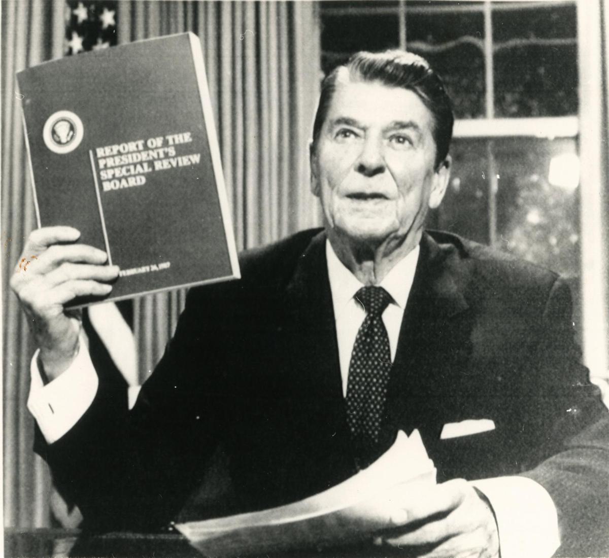 CONTROVERSIAL AFFAIR: U.S. President Ronald Reagan holds a copy of the Tower Commission Report on the Iran- Contra affair while posing for photographers in the Oval Office after he addressed the nation on television in Washington on August 12, 1987. Reagan said he was ‘mad as a hornet’ about damage to his administration from the Iran-Contra affair.