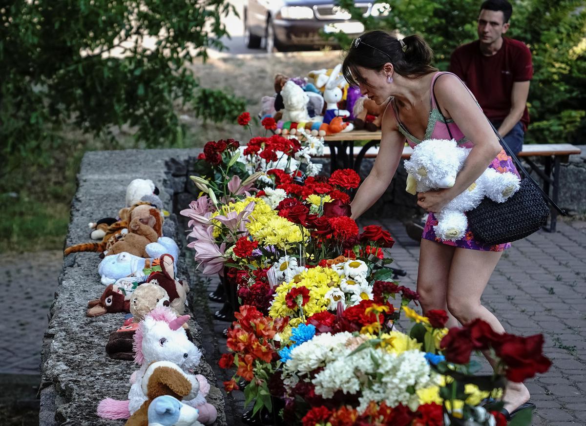 A woman lays flowers and a toy to commemorate victims of a shopping mall hit by a Russian missile strike, as Russia’s attack on Ukraine continues, in Kremenchuk, in Poltava region, Ukraine on June 28, 2022.