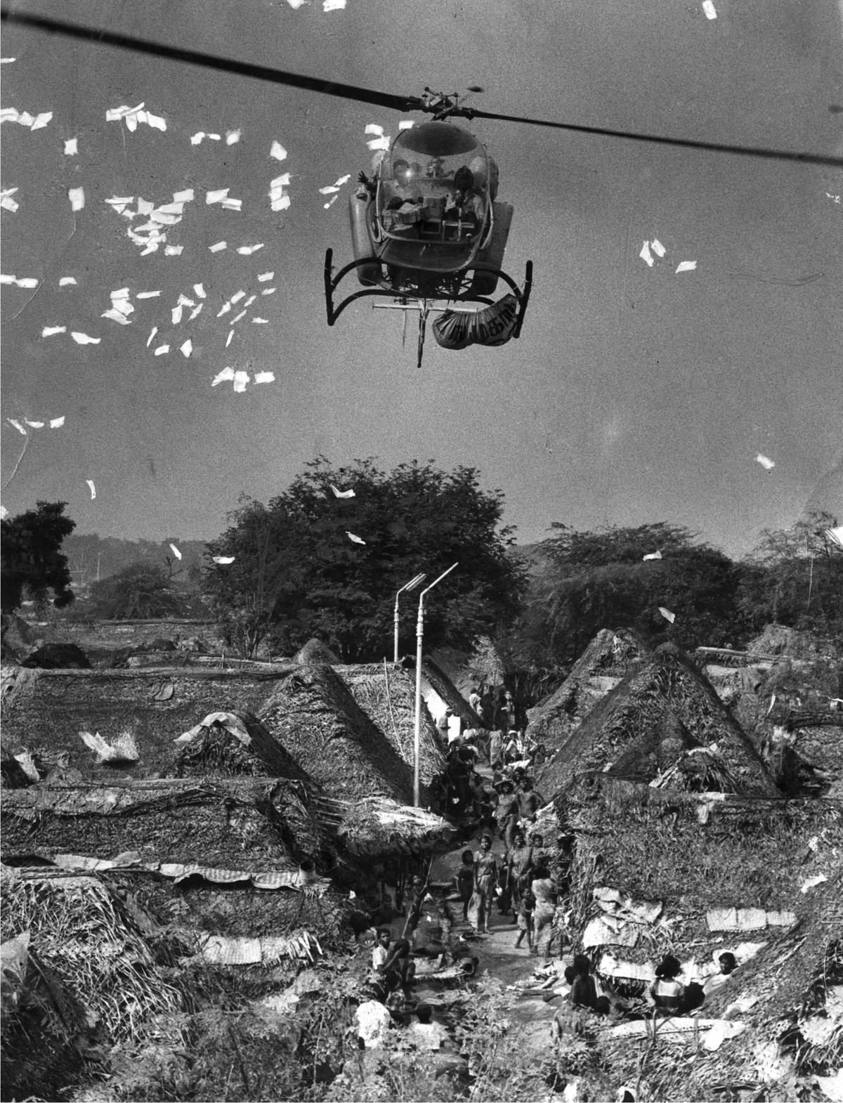 A helicopter dropping family planning pamphlets over a slum area near the Marmalong bridge, Saidapet in Madras, the capital of Tamil Nadu in December 1975.