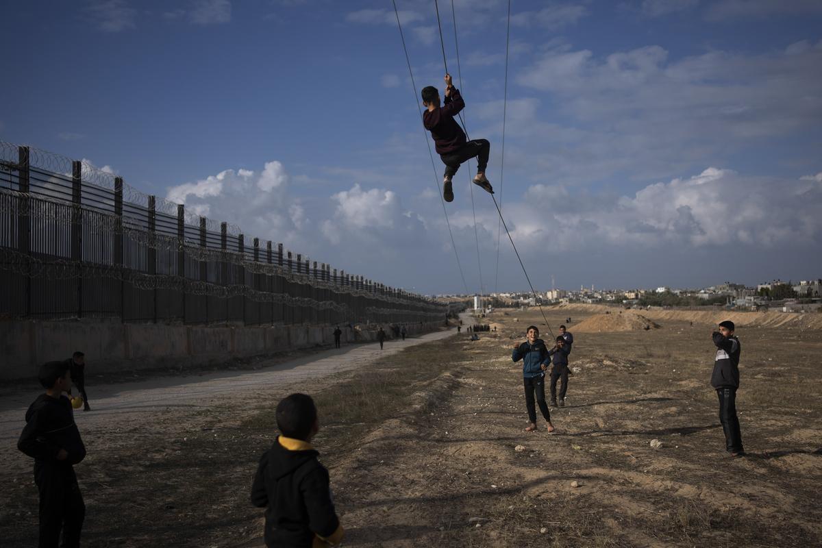 Palestinians displaced by the Israeli bombardment of the northern Gaza Strip play next to the border with Egypt, in Rafah, along the Philadelphi corridor, southern Gaza on January 14, 2024.