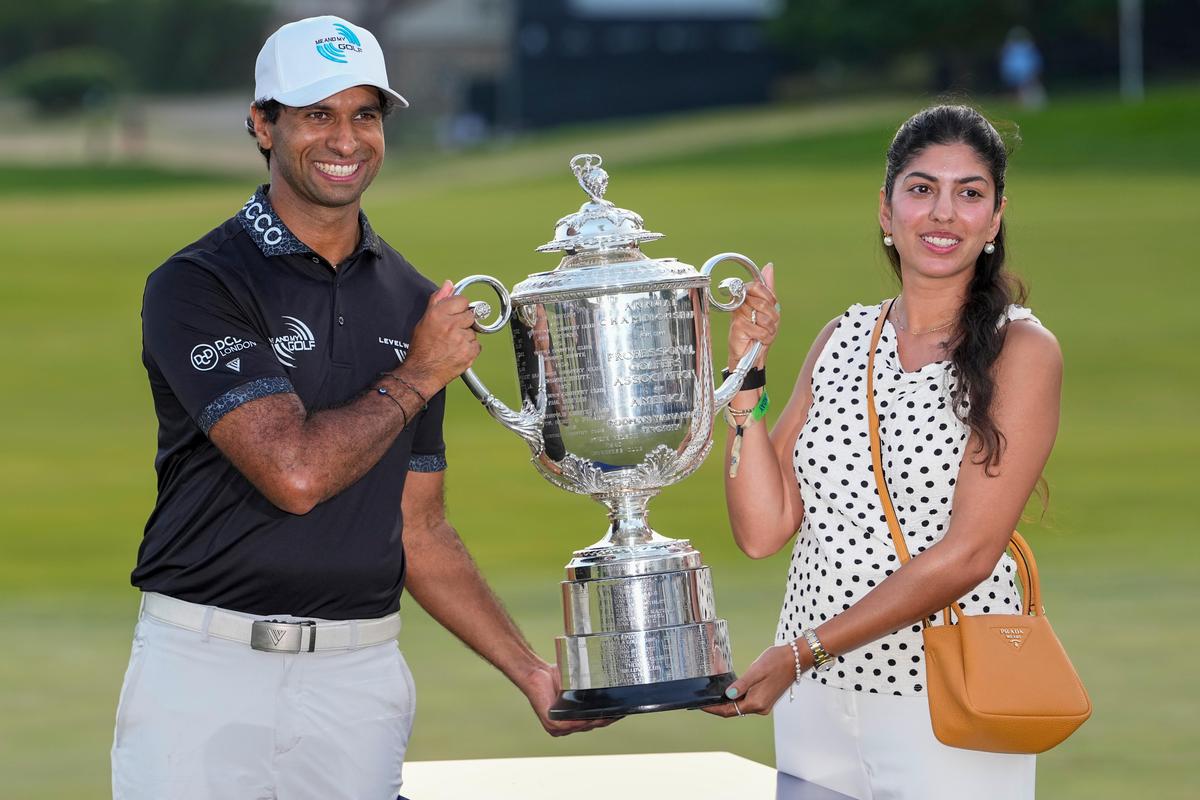 Aaron Rai, of England, and wife Gaurika Bishnoi hold the Wanamaker Trophy