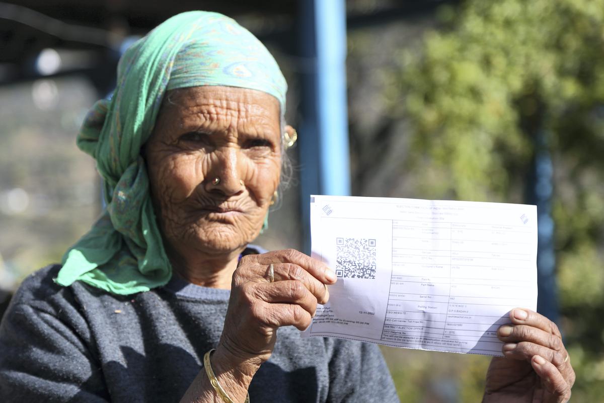 An elderly voter shows her voter ID card before casting her vote for Himachal Pradesh Assembly elections, at a polling station in Kullu, November 12, 2022