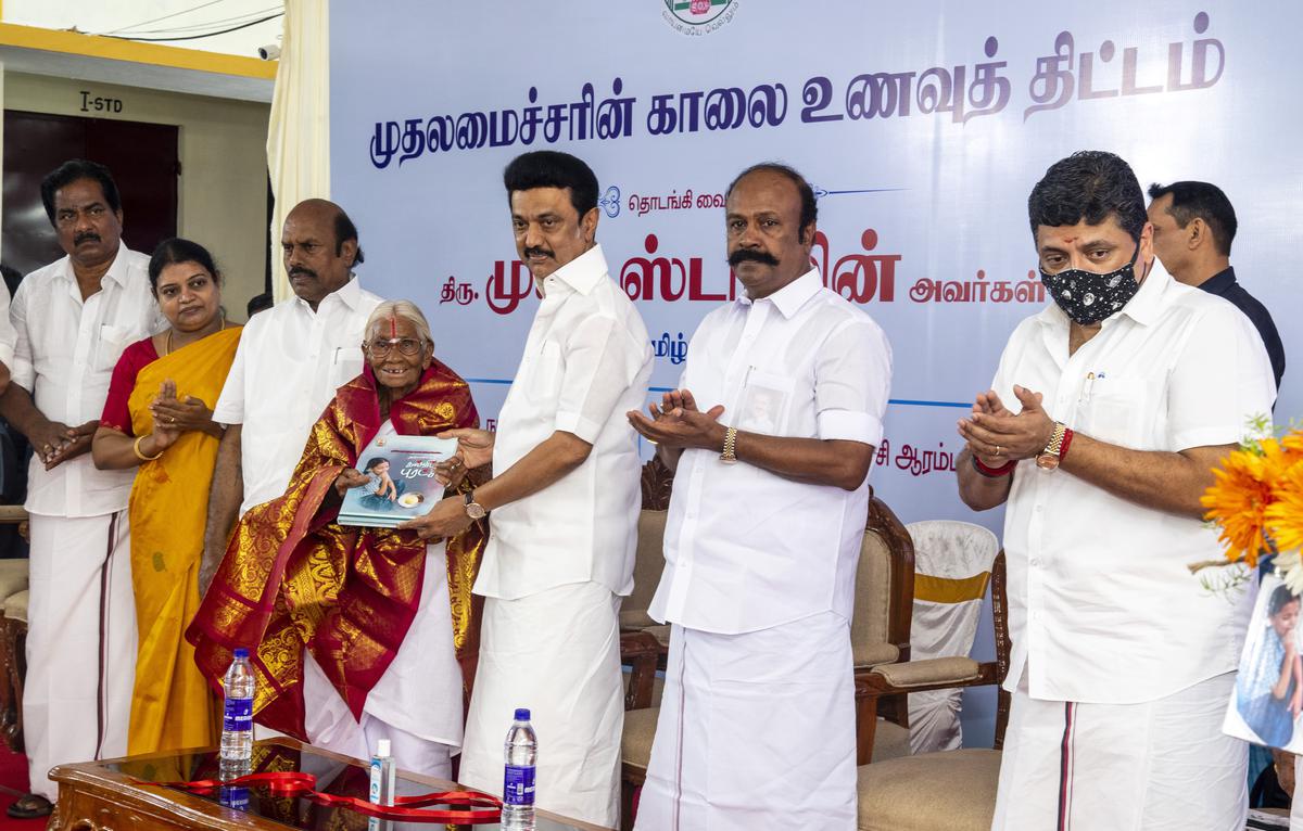 Tamil Nadu Chief Minister M.K. Stalin handing over the first copy of the book titled ‘Educational Revolution of a Century’ to M. Kamalathal, who has been selling idly for ₹1 for more than 30 years in Coimbatore, during the inauguration of Chief Minister’s Breakfast Scheme, in Madurai on September 15, 2022