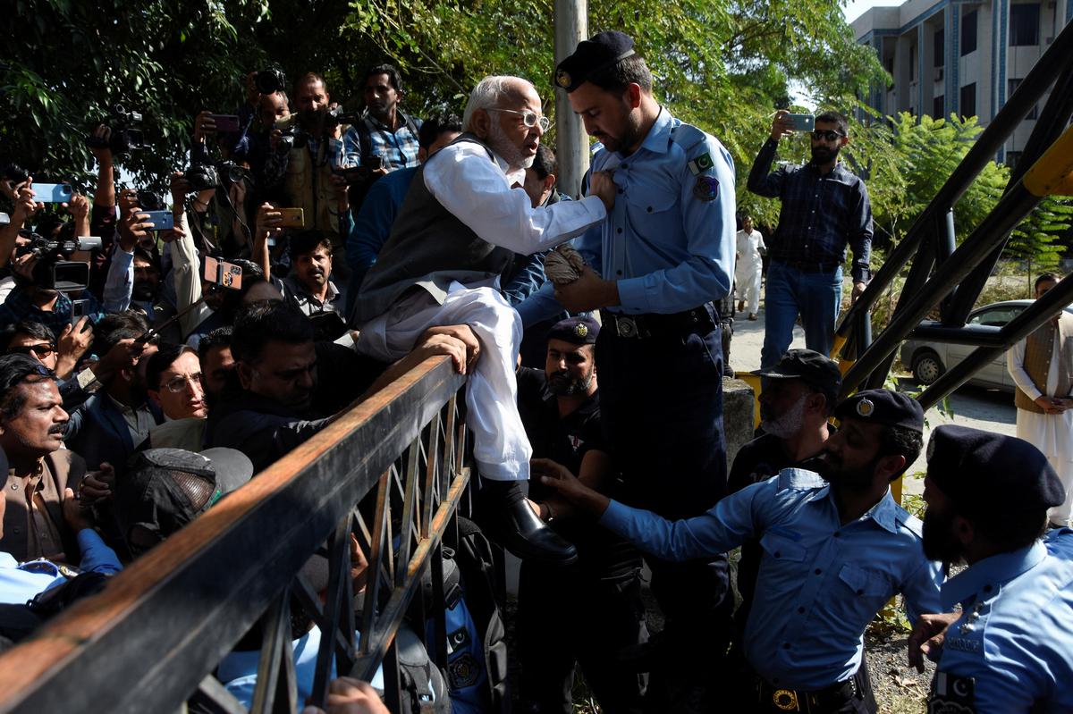 Police officers try to stop the supporters of the Pakistan Tehreek-e-Insaf (PTI) political party, after Pakistan Election Commission disqualified former Prime Minister Imran Khan on charges of unlawfully selling state gifts, on October 21, 2022.
