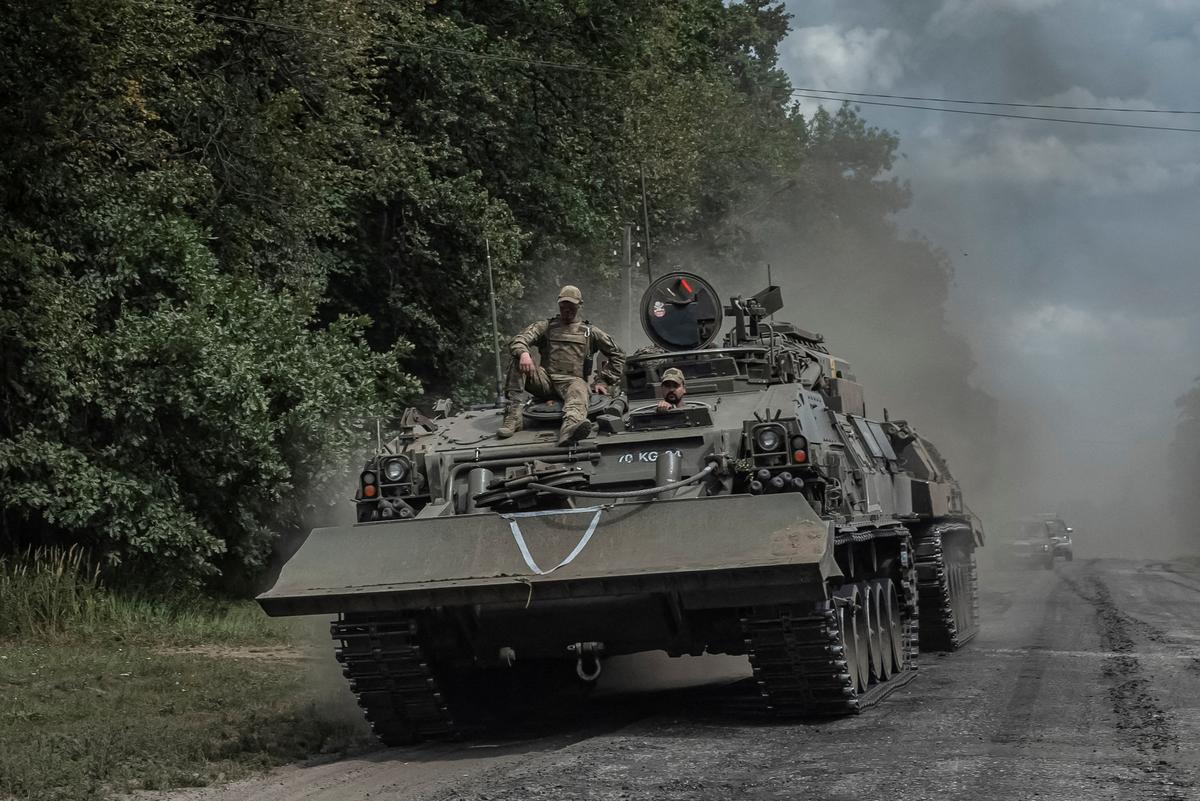  Ukrainian servicemen ride a military vehicle, amid Russia’s attack on Ukraine, near the Russian border in Sumy region.