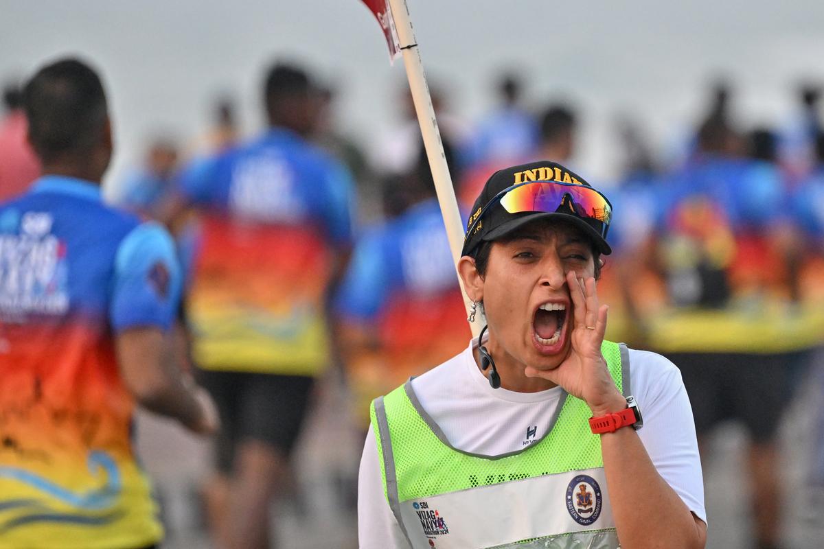 A volunteer cheering participants during the Vizag Navy Marathon 2024, organised by the Indian Navy at the Beach Road in Visakhapatnam on Sunday.