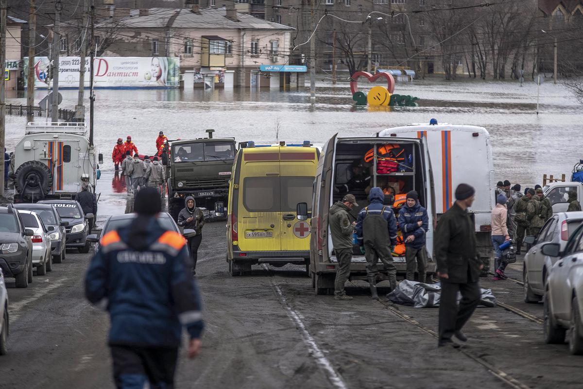 Emergency workers gather near their vehicles during evacuations in a flooded street after parts of a dam burst, in Orsk, Russia, on April 8, 2024. Emergency workers gather near their vehicles during evacuations in a flooded street after parts of a dam burst, in Orsk, Russia, on April 8, 2024.