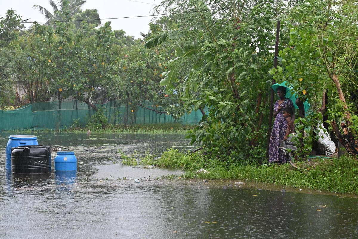 A woman and child wait for help on a flooded street in Gandhi Nagar, Vedaranyam after heavy rain under the influence of Cyclone . 