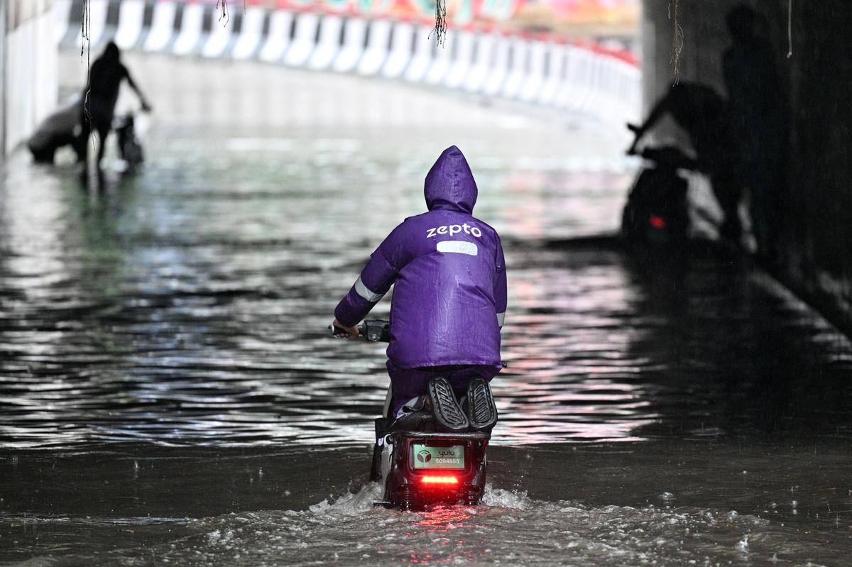 A delivery service worker wading through an inundated underpass.