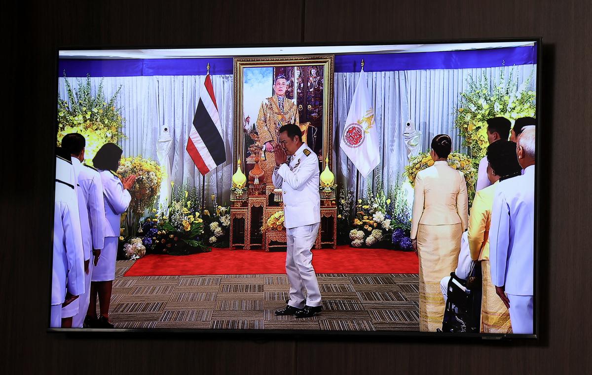 A screen shows Thailand’s Prime Minister Anutin Charnvirakul gesturing in front of a portrait of Thai King Maha Vajiralongkorn during a royal endorsement ceremony in Bangkok on September 7, 2025.