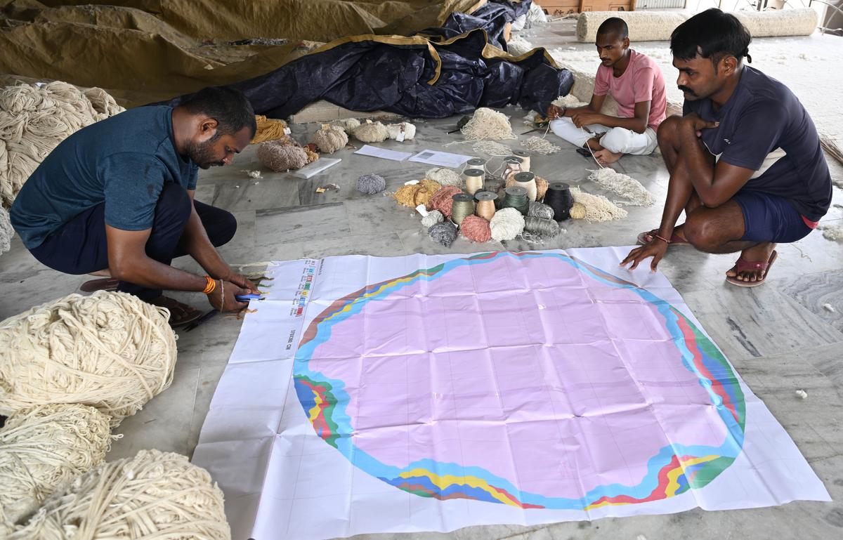 Un trabajador que coloca muestras de hilo en el mapa de diseño de alfombras. 