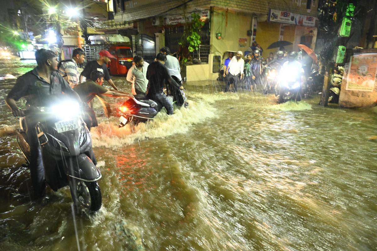 हैदराबाद में हुई भारी बारिश के बीच सड़क पार करते यात्री और पैदल यात्री।