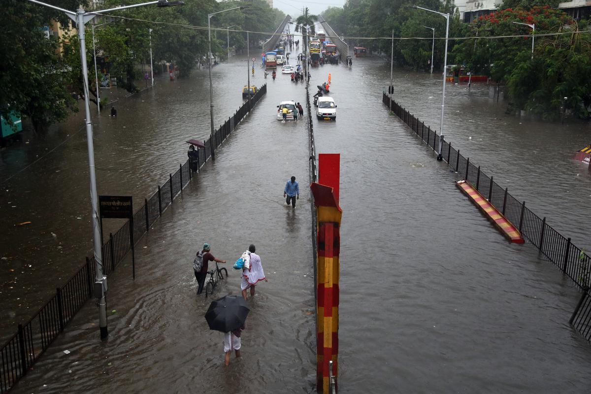 People walk on a flooded road in Sion, Mumbai, June 9, 2021.