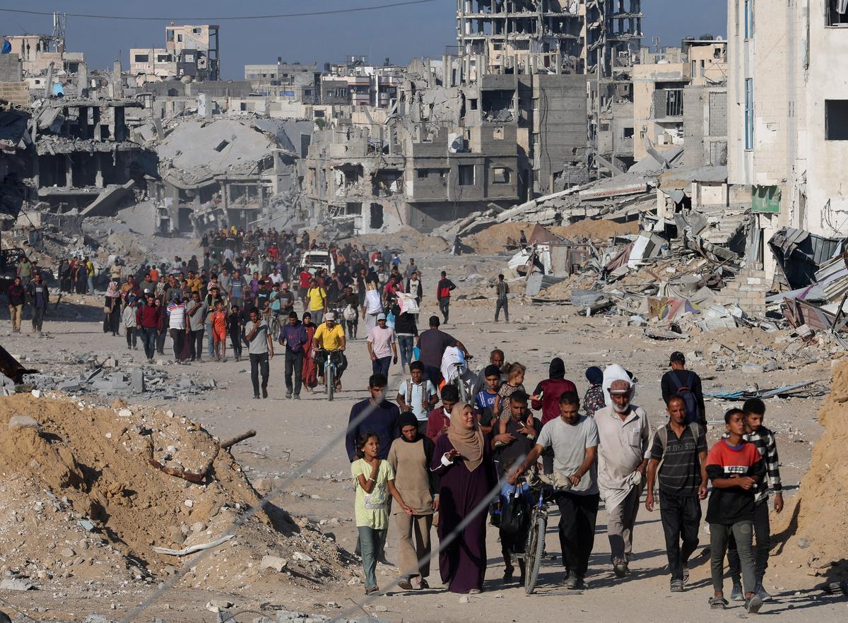 Palestinians walk past rubble as they return to their neighborhood, following Israeli forces’ withdrawal from the area, amid a ceasefire between Israel and Hamas in Gaza, in Khan Younis, in the southern Gaza Strip on October 11, 2025. 