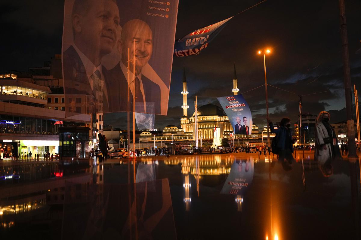 Pedestrians walk past a giant banner of Turkish President and People’s Alliance’s presidential candidate Recep Tayyip Erdogan, left, and Turkish CHP party leader and Nation Alliance’s presidential candidate Kemal Kilicdaroglu, background right, at Taksim square in Istanbul on May 10, 2023.