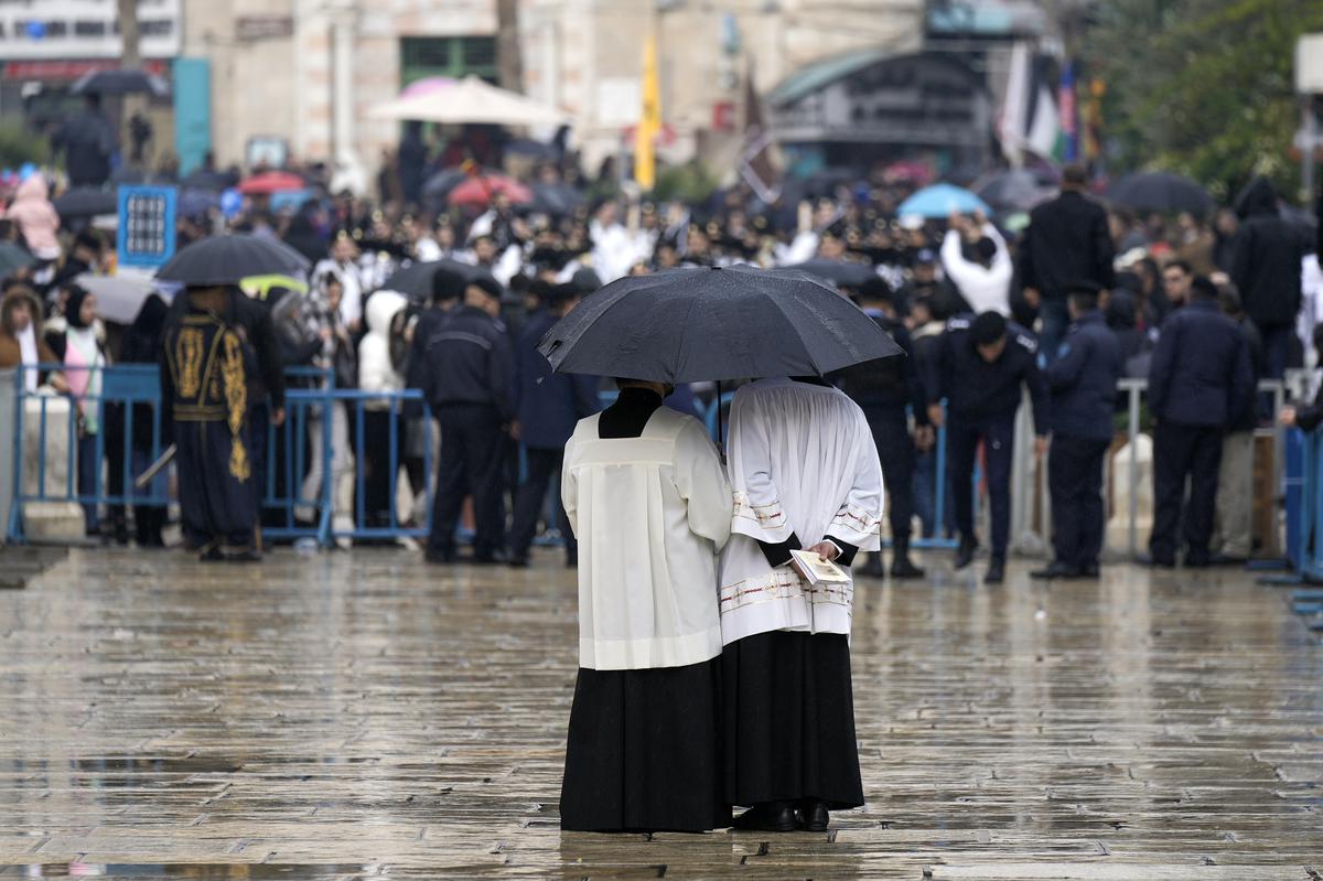Two clergymen wait for Latin Patriarch Pierbattista Pizzaballa in Manger Square, adjacent to the Church of the Nativity, traditionally believed to be the birthplace of Jesus Christ, in the West Bank town of Bethlehem during Christmas celebrations on December 24, 2022.