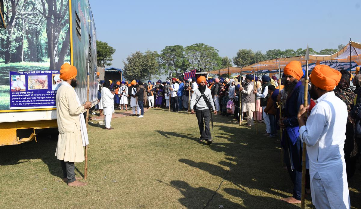 followers wait to catch a glimpse of the self-styled Sikh preacher outside his caravan.