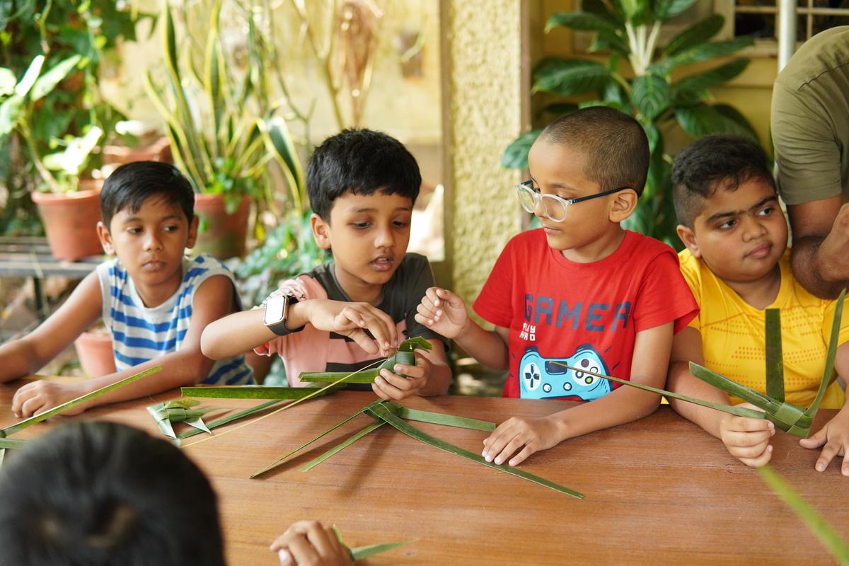 Participants of Thalir summer camp in Thiruvananthapuram learning to make toys from coconut fronds.