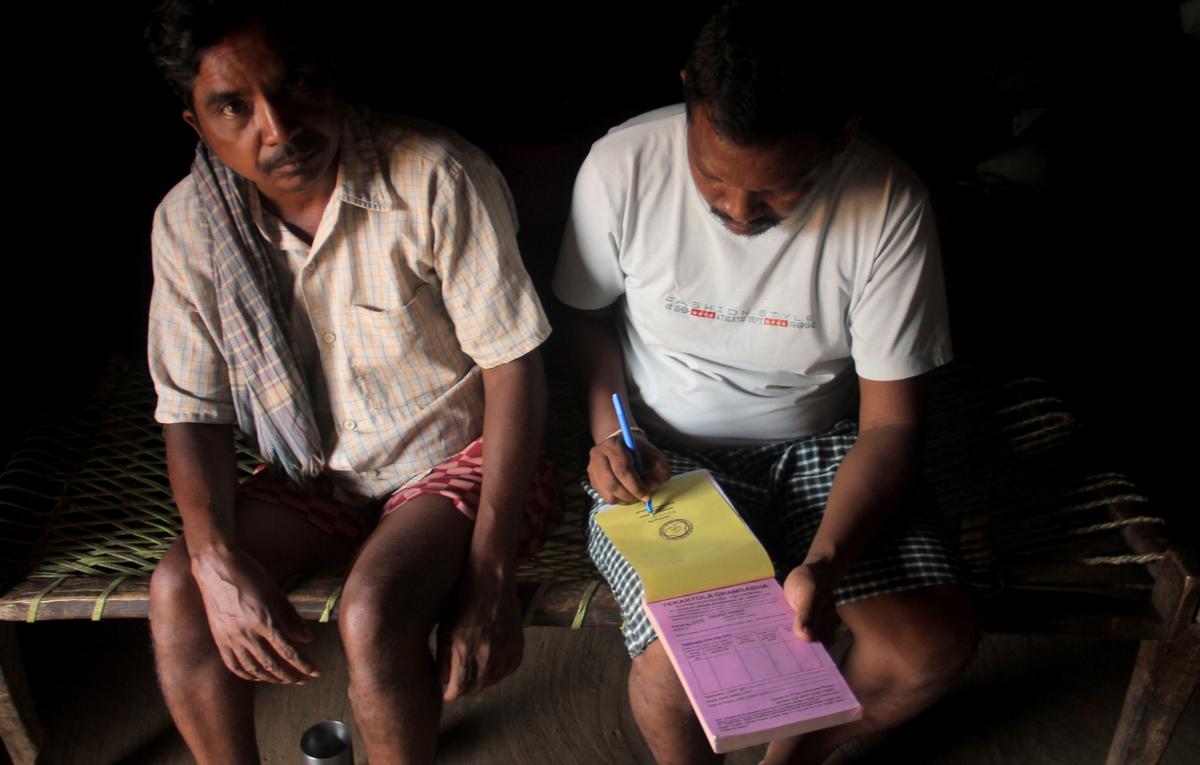 Byasadev Majhi (right), secretary of the Kalahandi Gram Sabha Mahasangha, issuing a transit pass for kendu and bamboo trucks at Pipadi village.