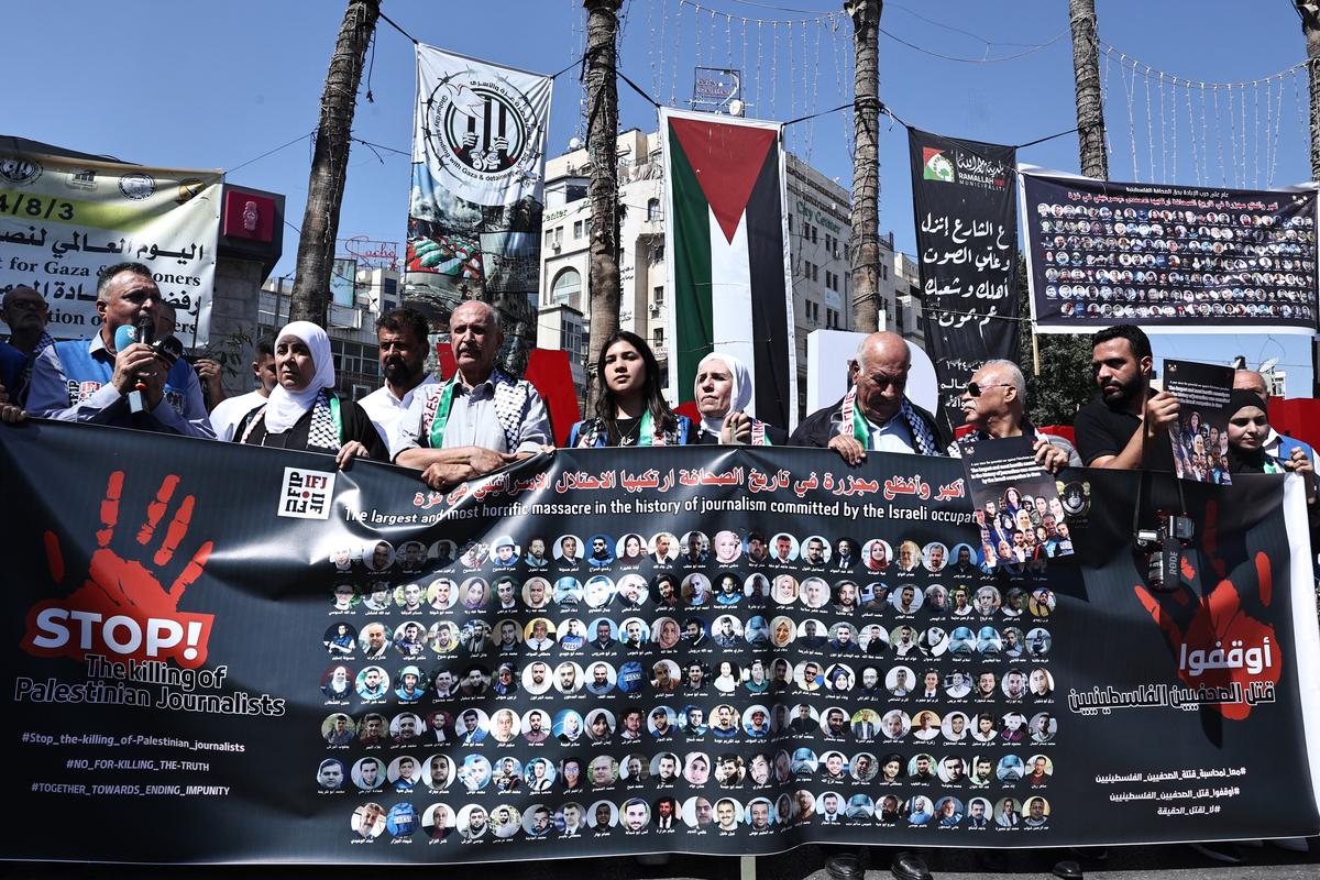 Protesters carry a banner, and posters bearing pictures of slain Palestinian journalists during a rally to condemn their killing, in Ramallah in the occupied West Bank on October 6, 2024.